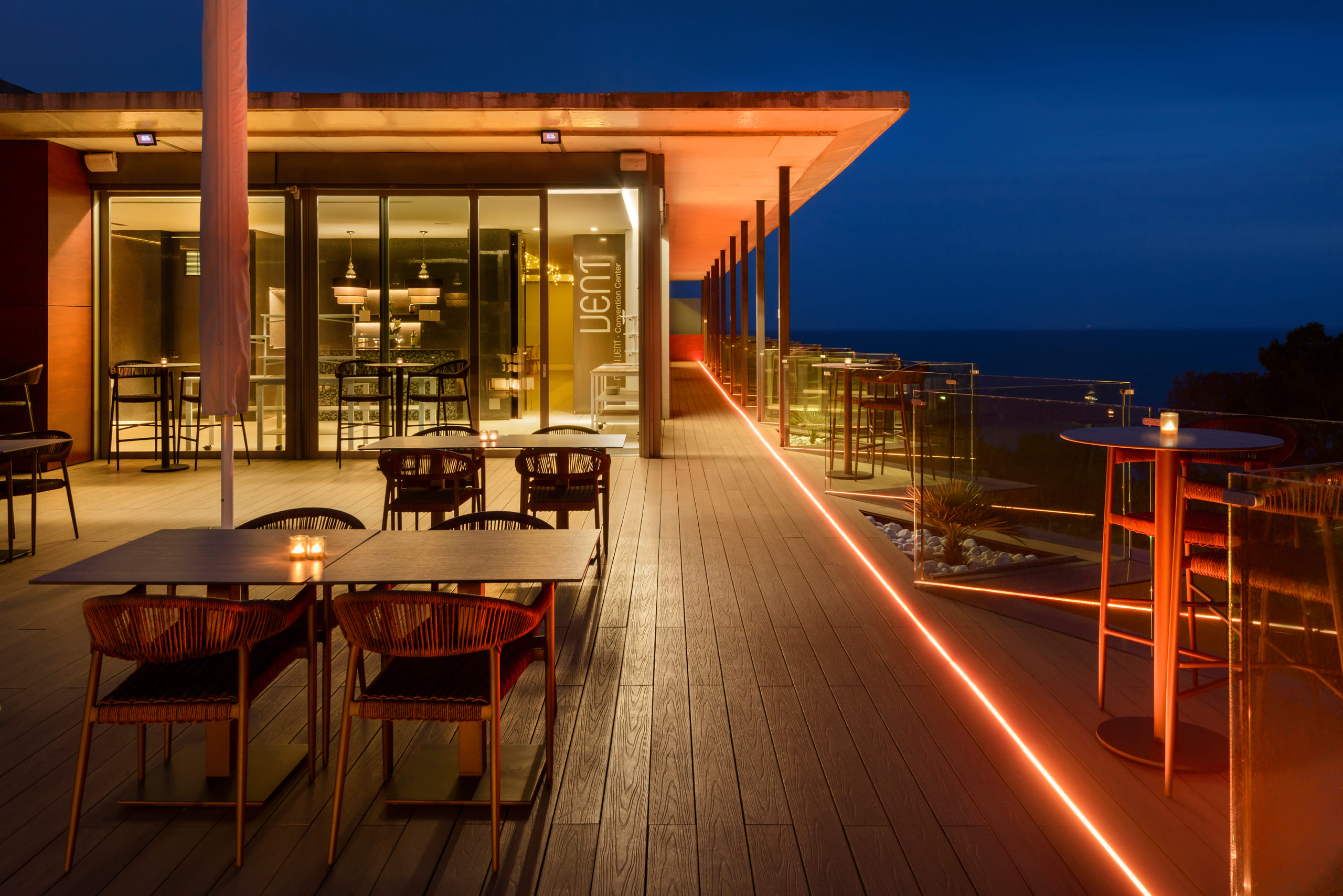 Die Terrasse des Barceló Illetas Albatros zur blauen Stunde, Kerzen auf den Tischen, eine warme Lichtlinie entlang der Glasbrüstung, dahinter das Meer
